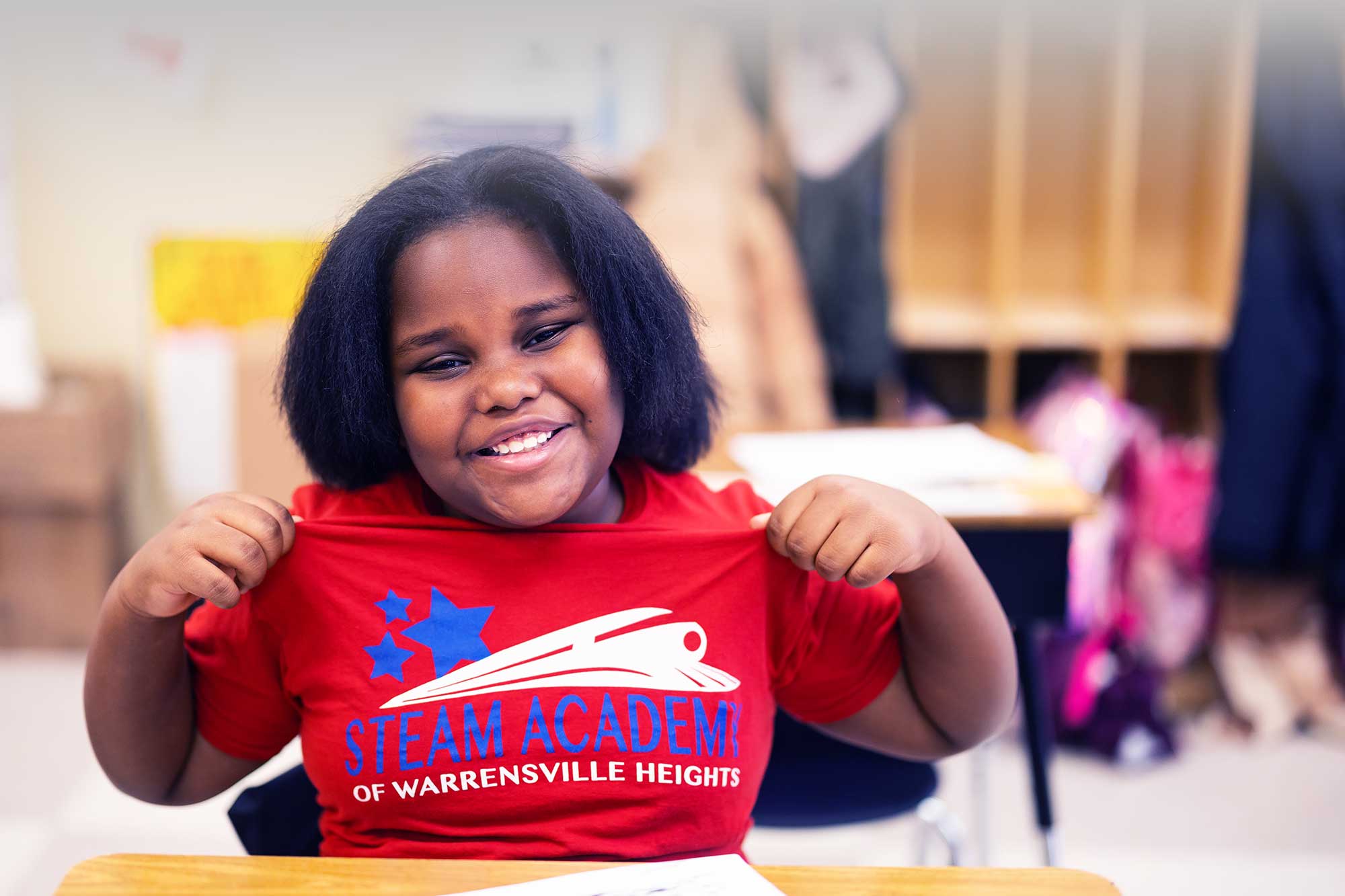 Smiling student showing off their STEAM Academy of Warrensville Heights shirt.